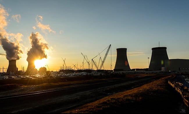 The sun sets behind the Vogtle 1 and 2 cooling towers near the Unit 3 and 4 construction site in Georgia. Courtesy: Georgia Power (March 2016)